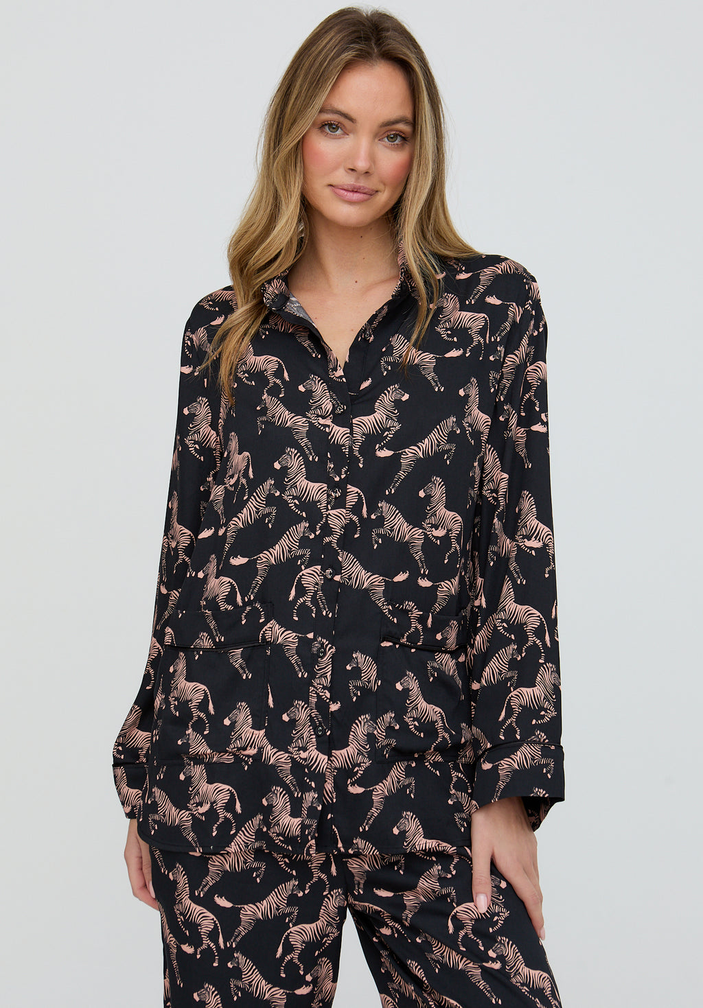 Woman wearing a black pajama set with animal pattern on a plain background