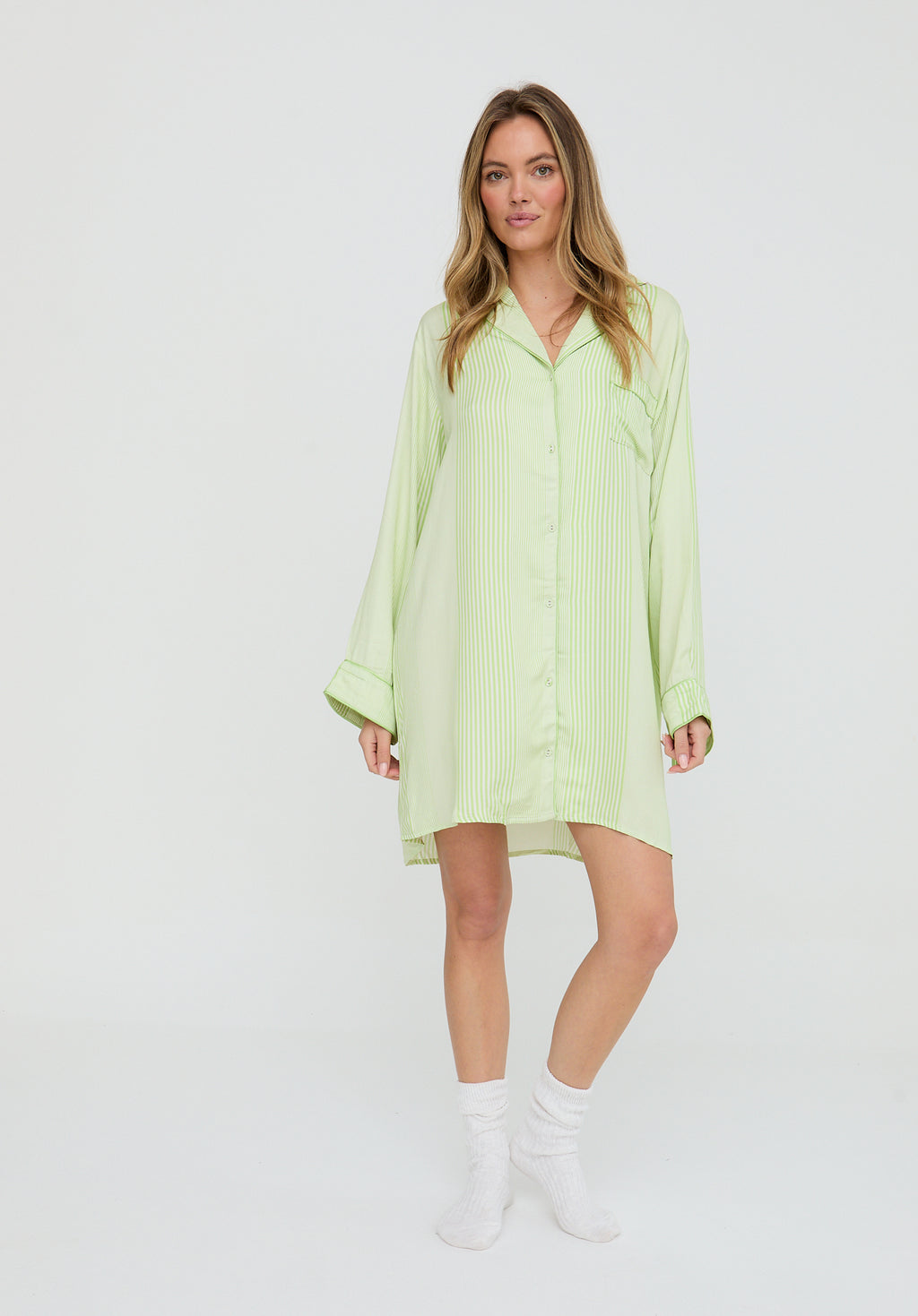 Woman wearing a light green shirt dress on a white background