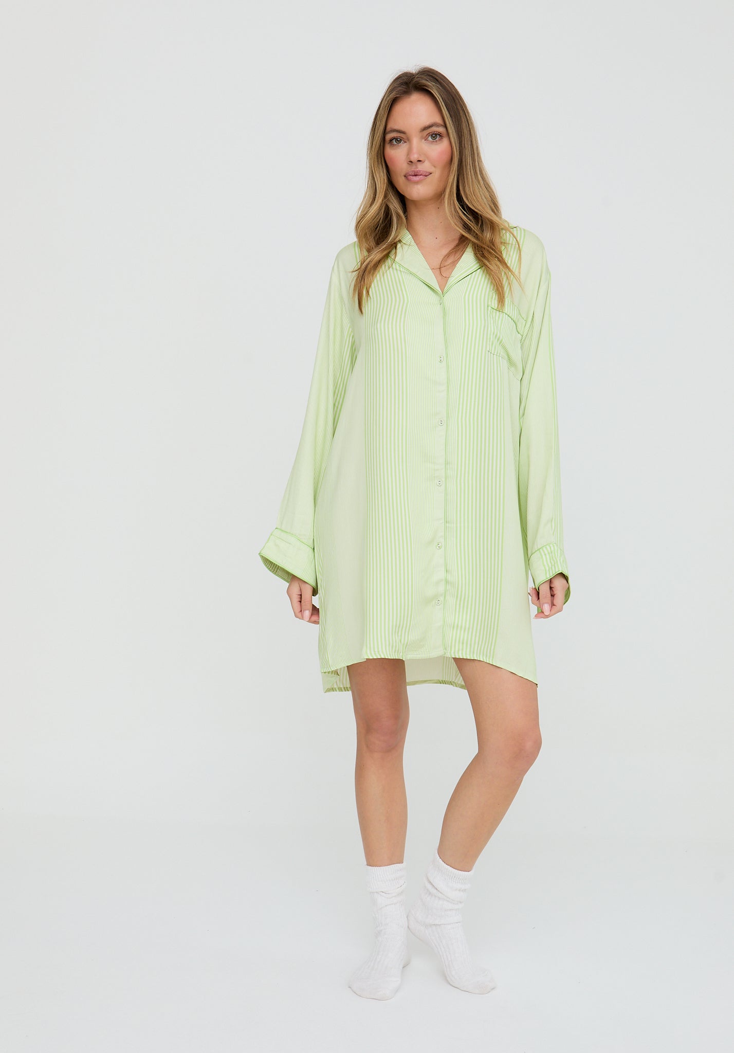 Woman wearing a light green shirt dress on a white background