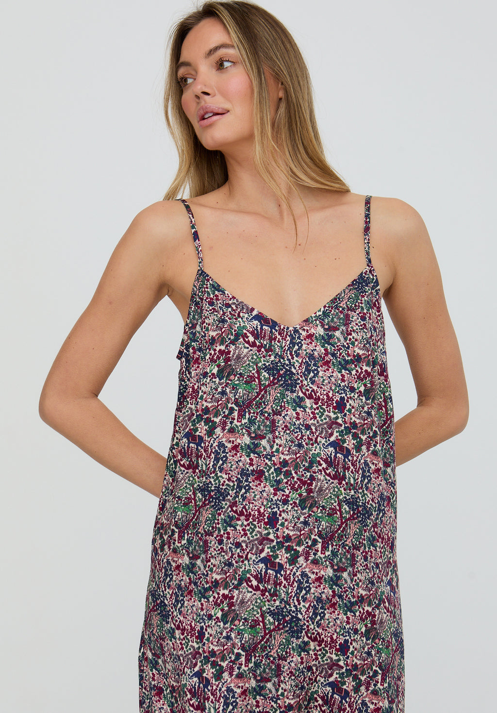 Woman wearing a floral slip dress against a plain background