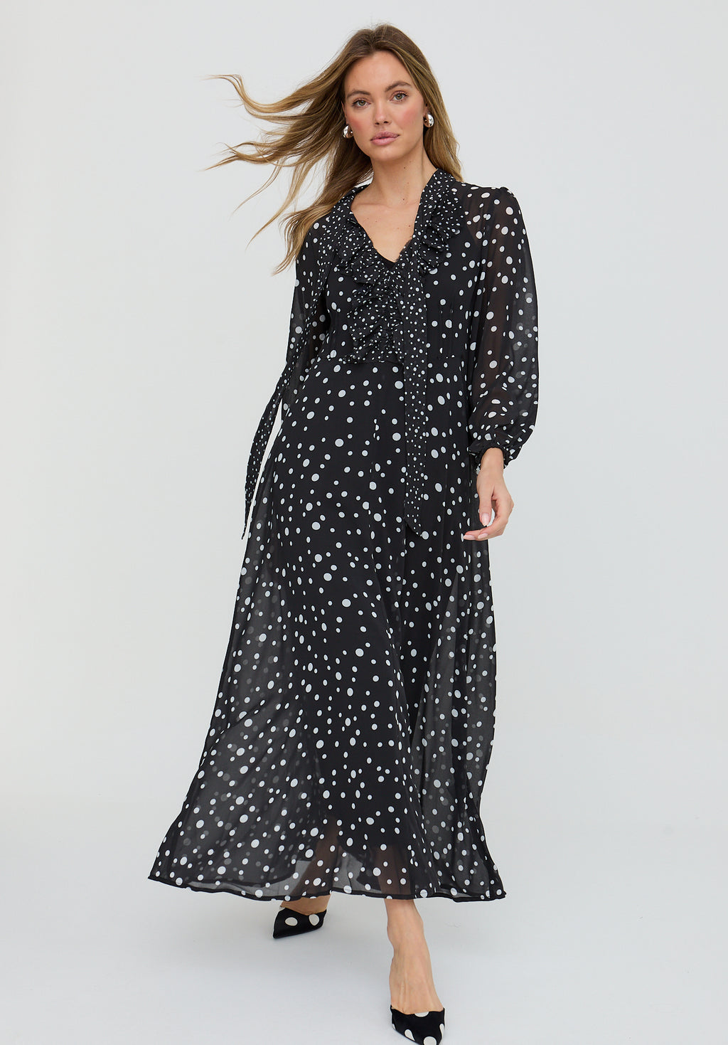 Woman wearing a black dress with white polka dots on a white background