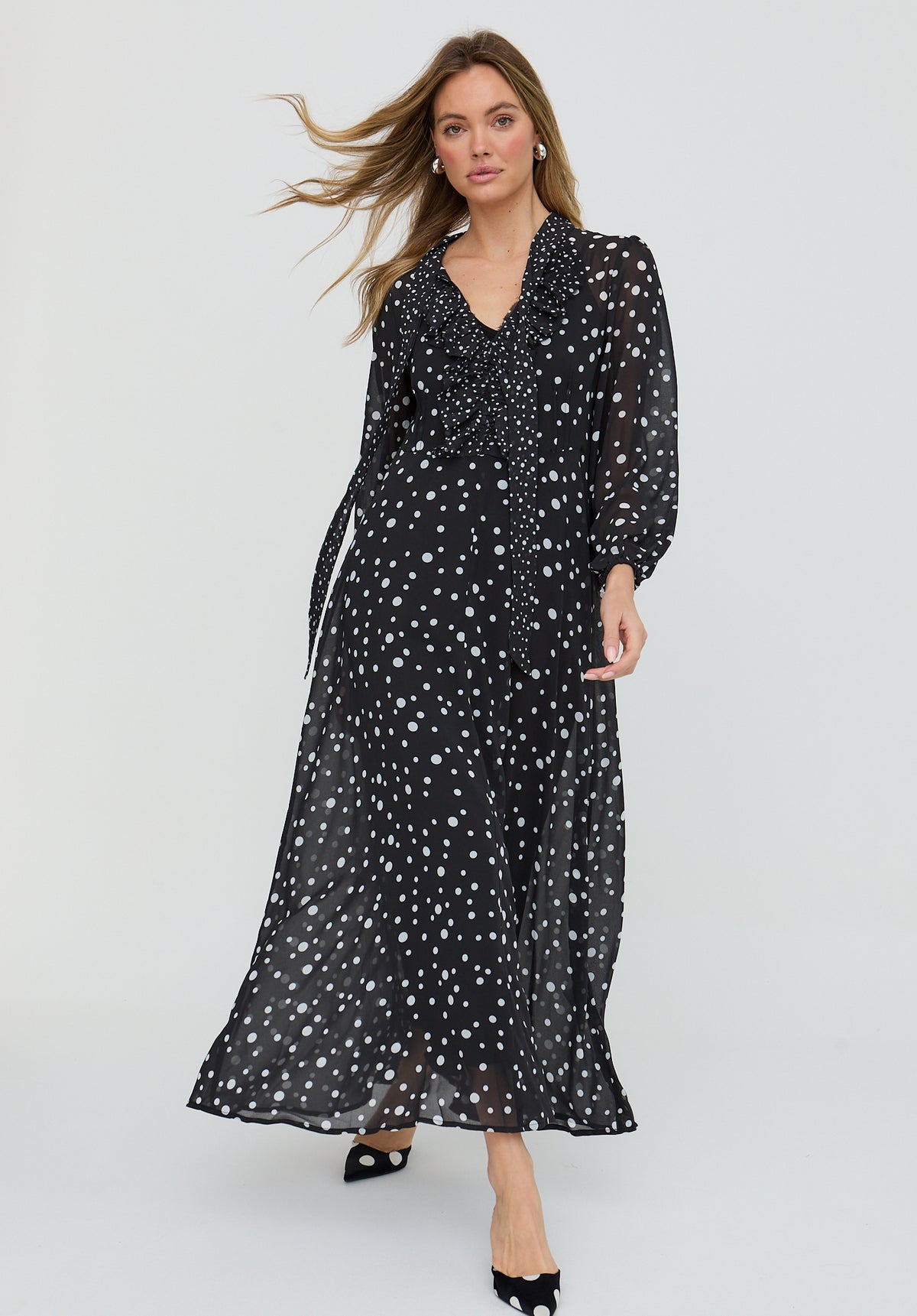 Woman wearing a black dress with white polka dots on a white background