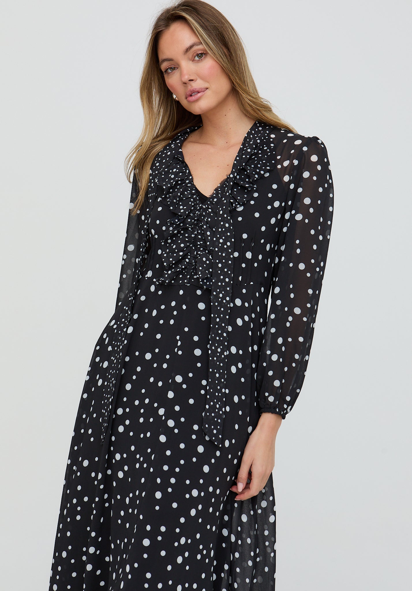 Woman wearing a black dress with white polka dots on a light gray background