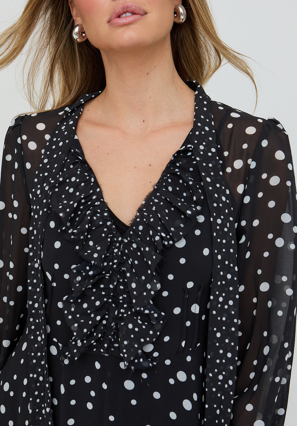 Black polka dot blouse with a deep neckline and tied front detail.