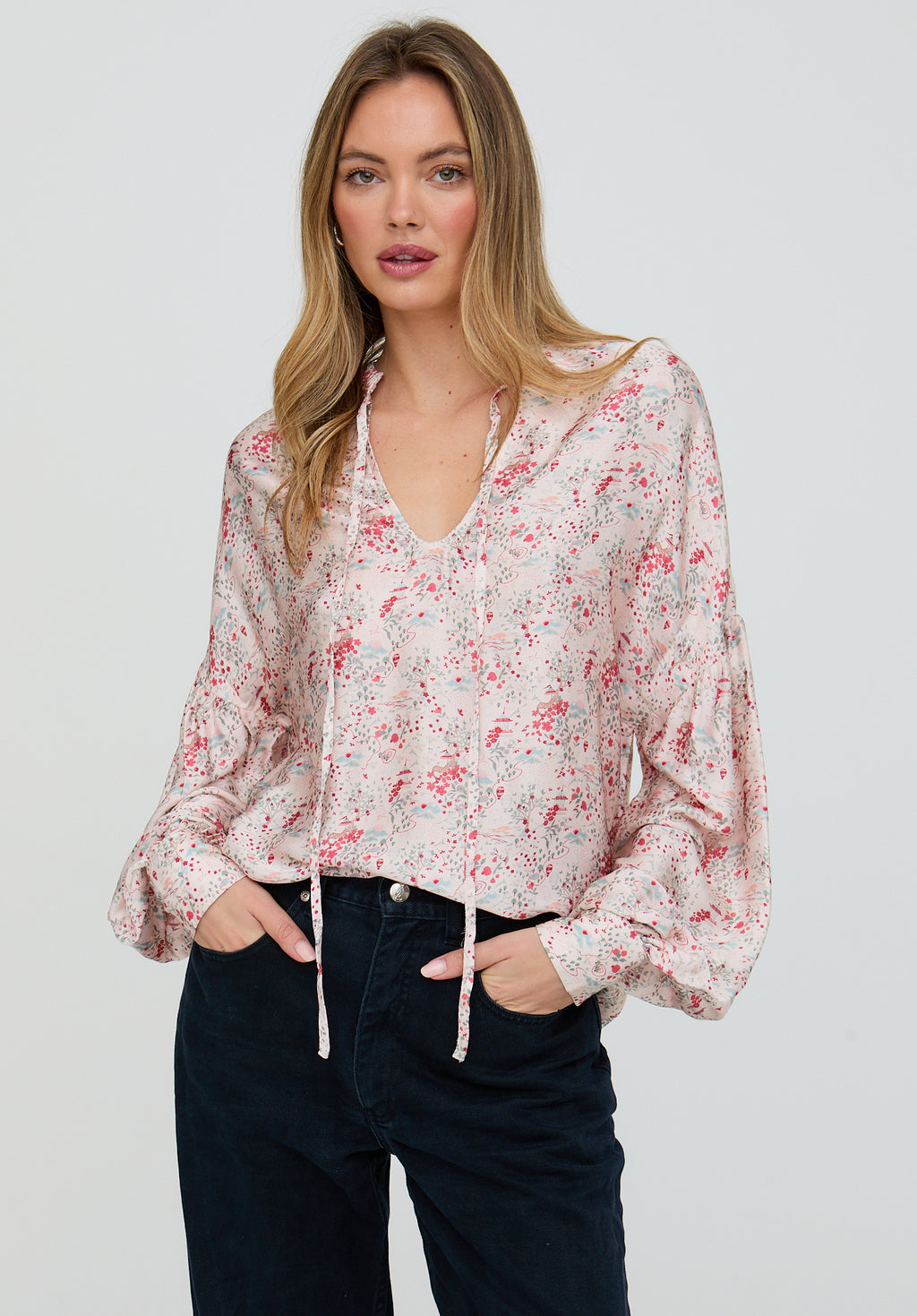 Woman wearing a floral blouse with long sleeves on a plain background