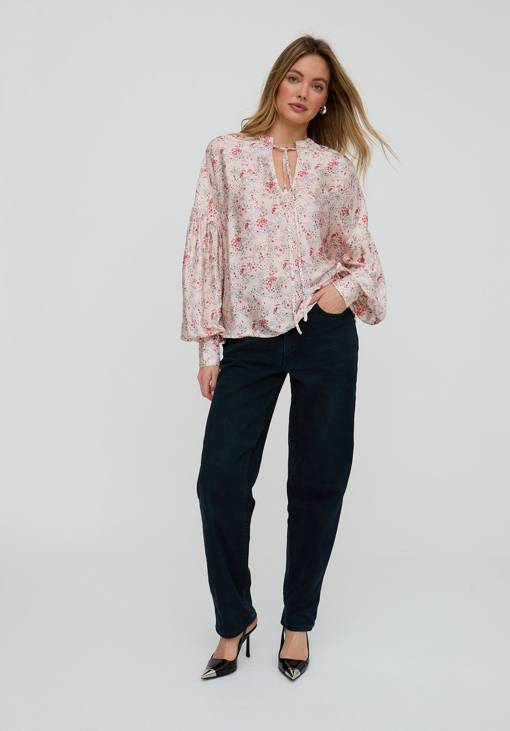 Woman wearing a floral blouse and black pants on a white background