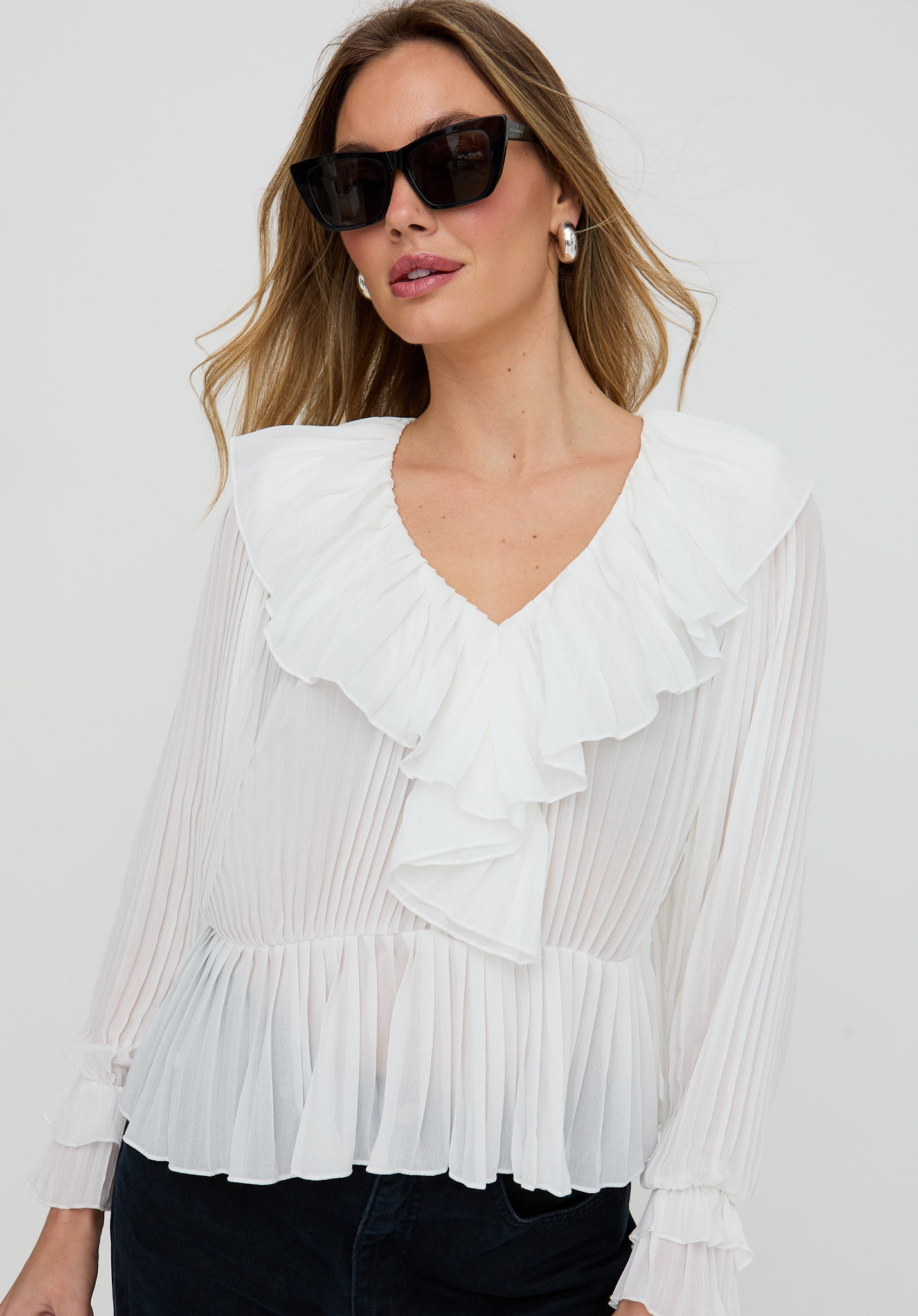 Woman wearing a white ruffled blouse against a plain background