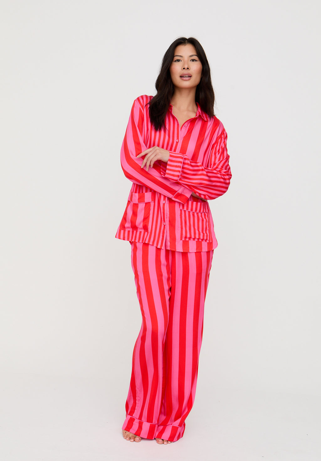 Woman wearing a red and pink striped pajama set on a white background