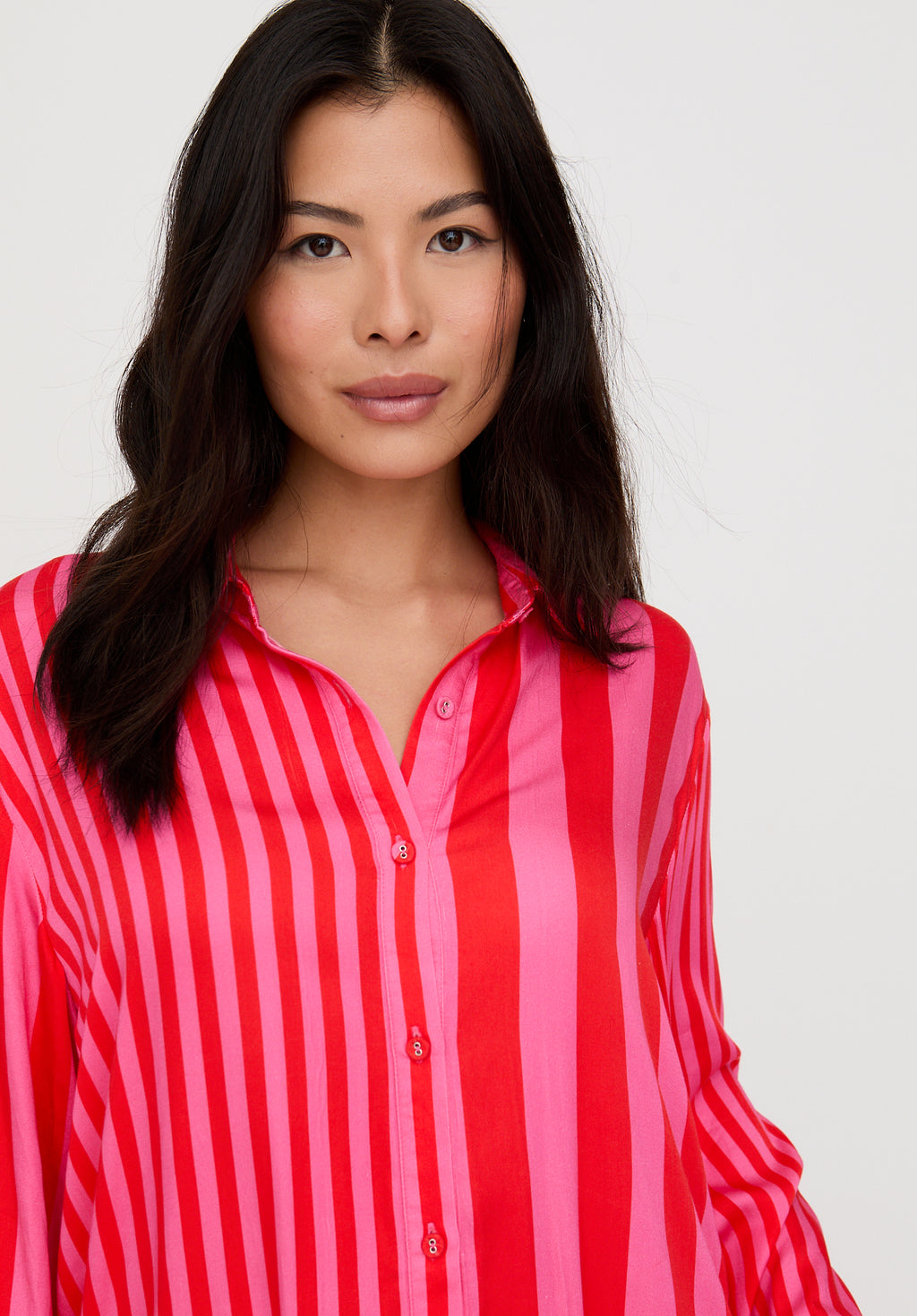 Woman wearing a red and pink striped shirt against a white background