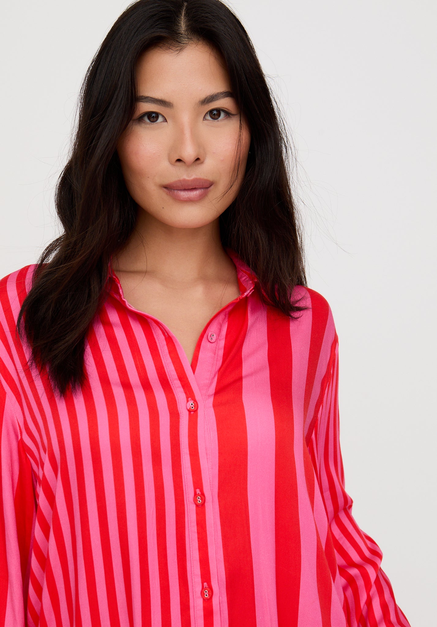 Woman wearing a red and pink striped shirt against a white background
