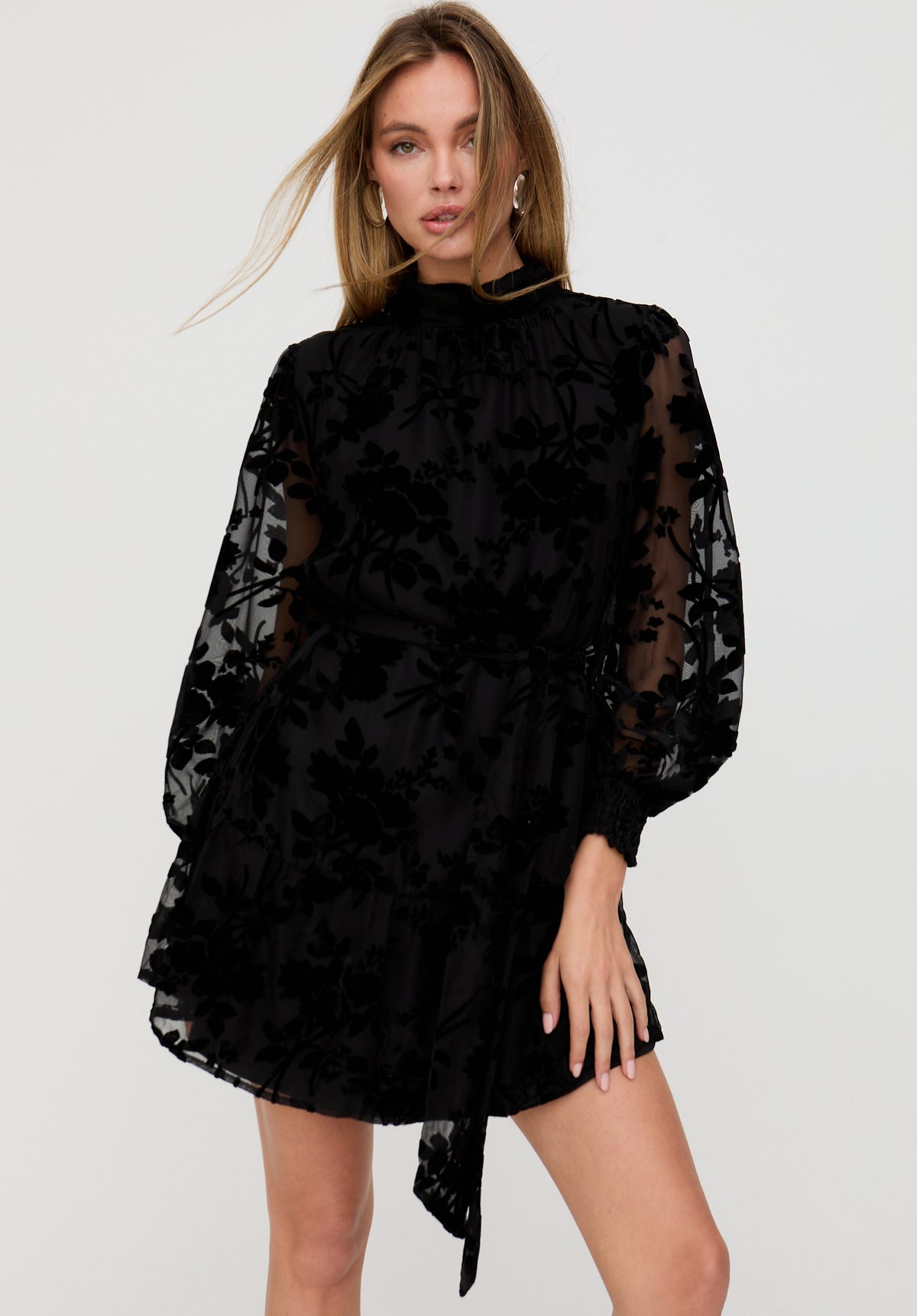 Woman wearing a black floral dress against a white background