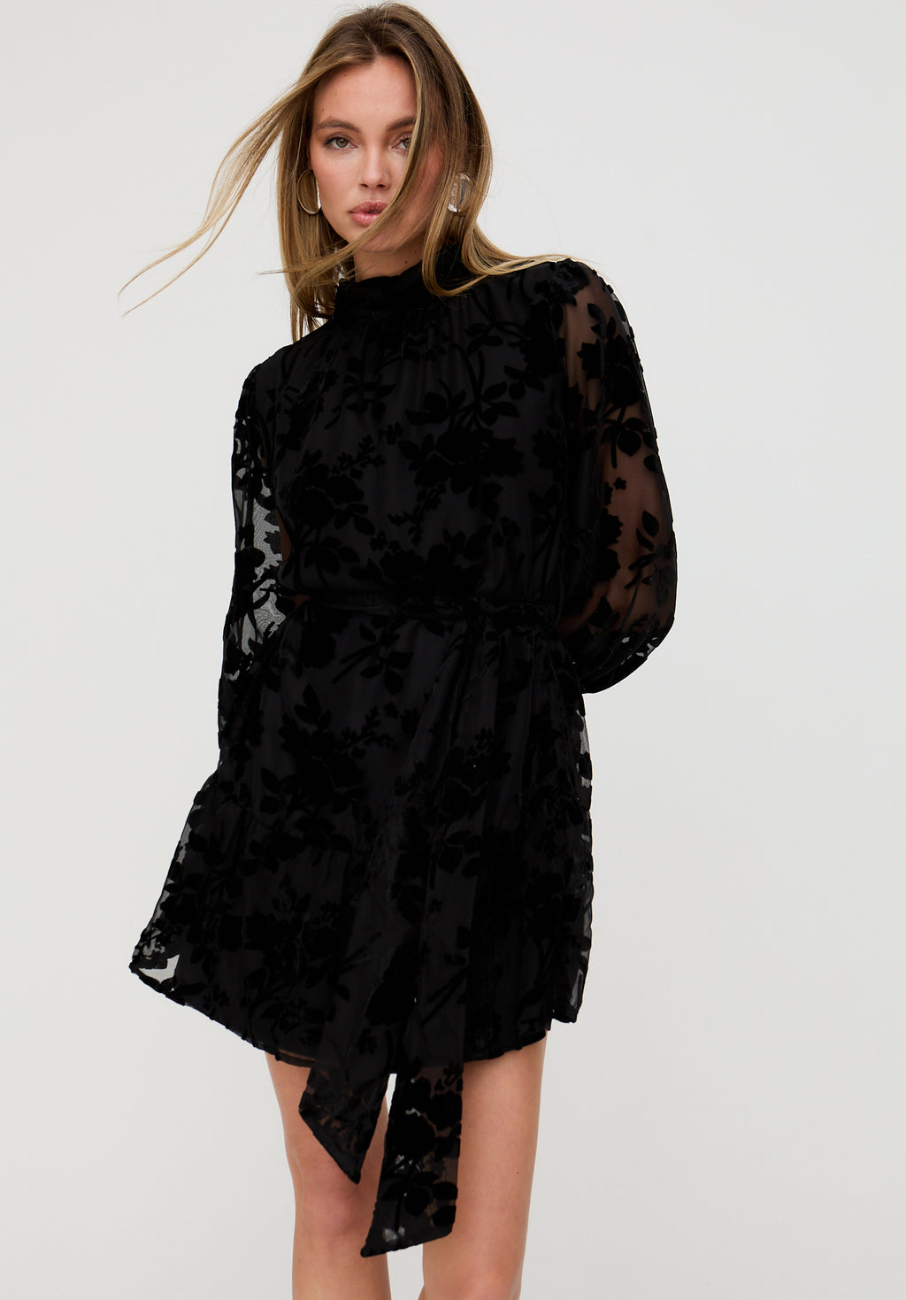 Woman wearing a black floral dress against a white background