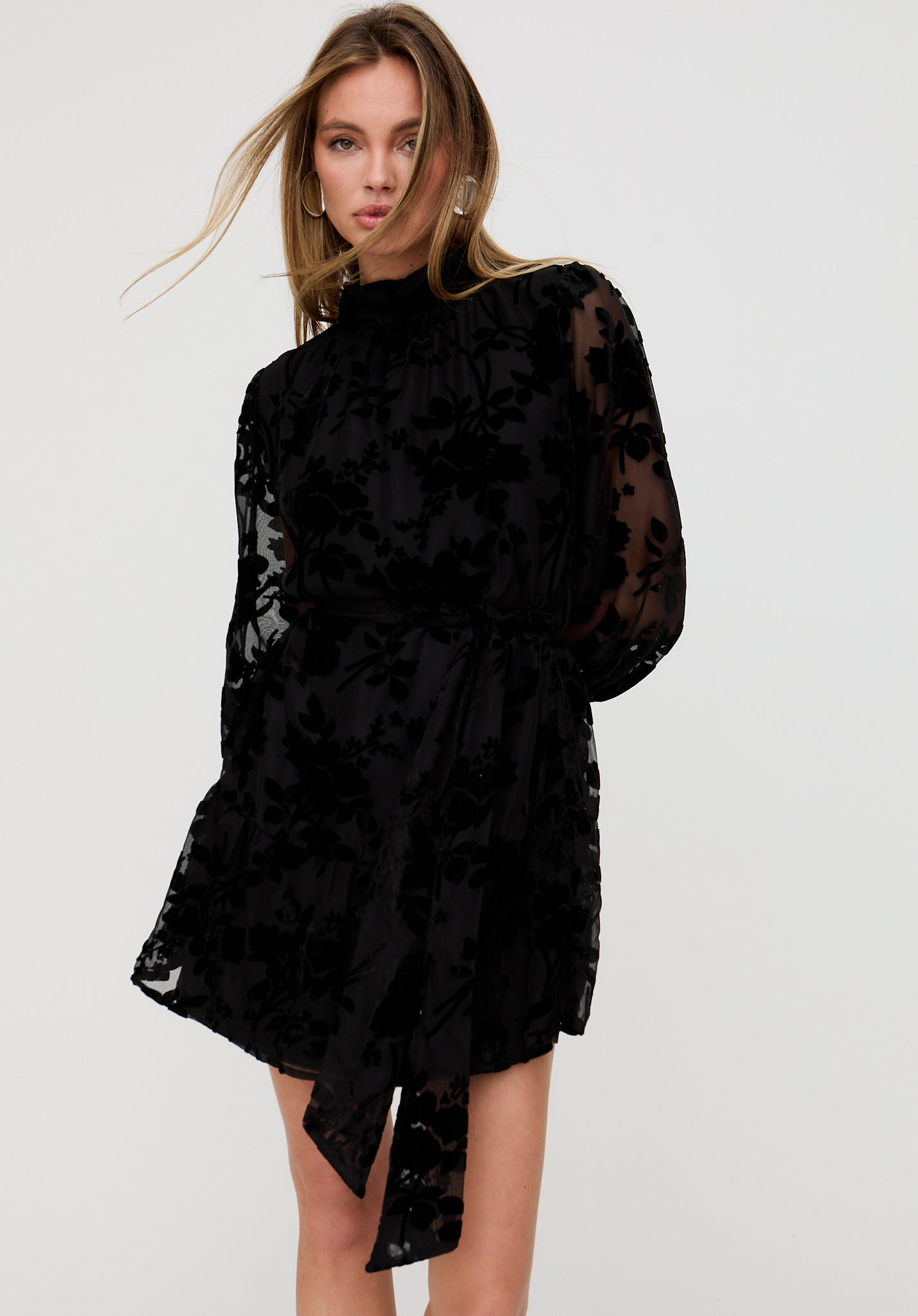 Woman wearing a black floral dress against a white background