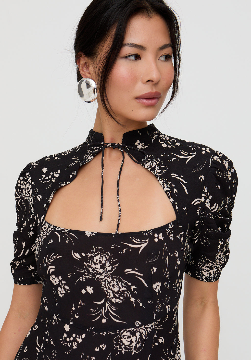 Woman wearing a black floral dress with a white background