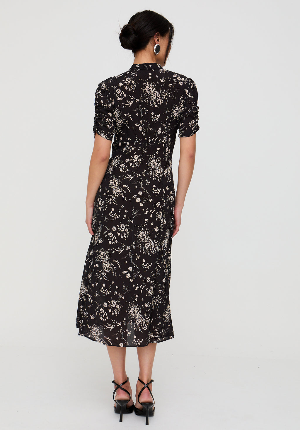 Woman wearing a black floral dress against a white background
