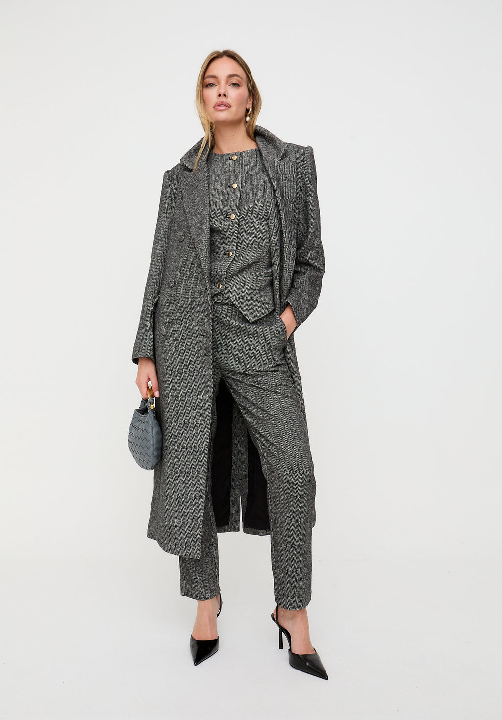 Woman wearing a gray coat and pants with a white background