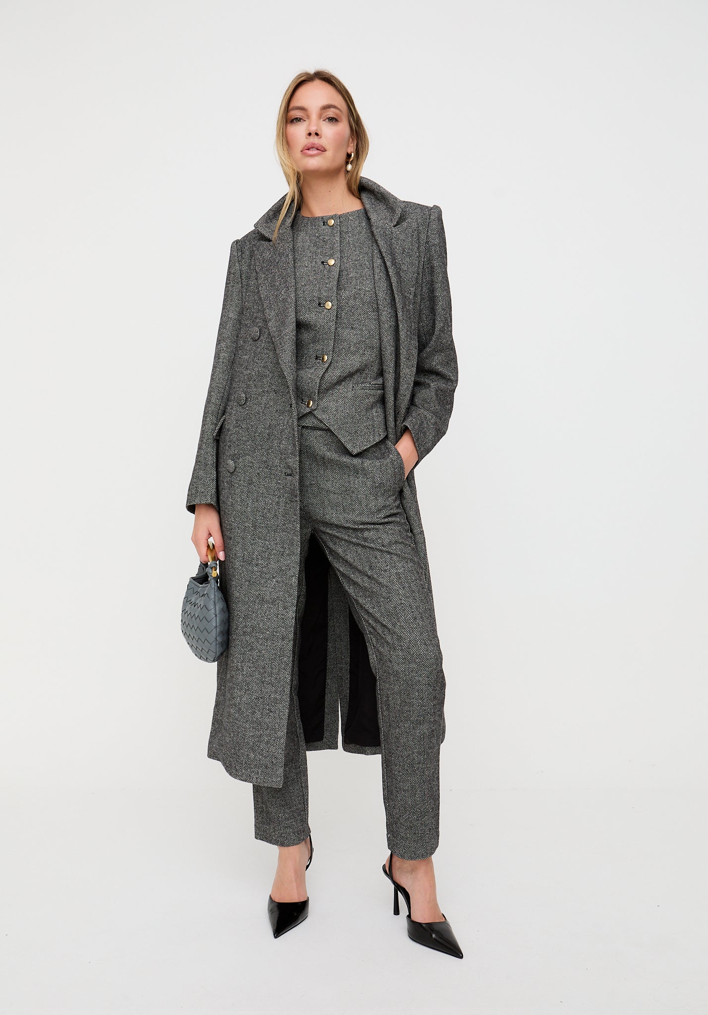 Woman wearing a gray coat and pants with a white background