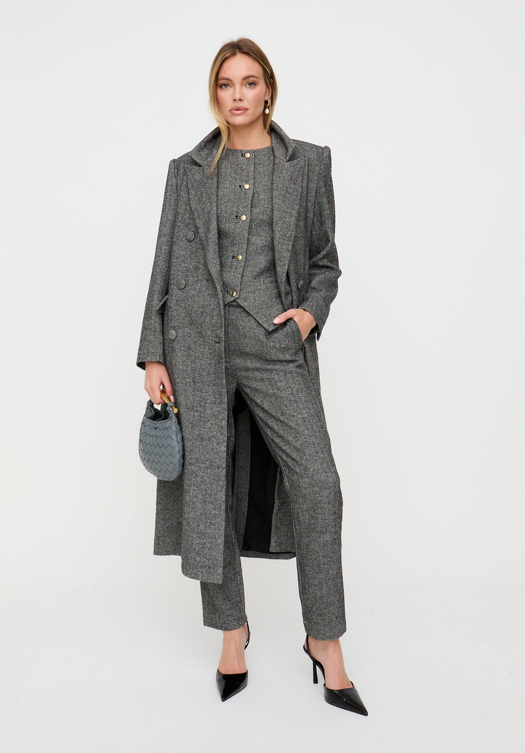 Woman wearing a gray suit with a long coat on a white background