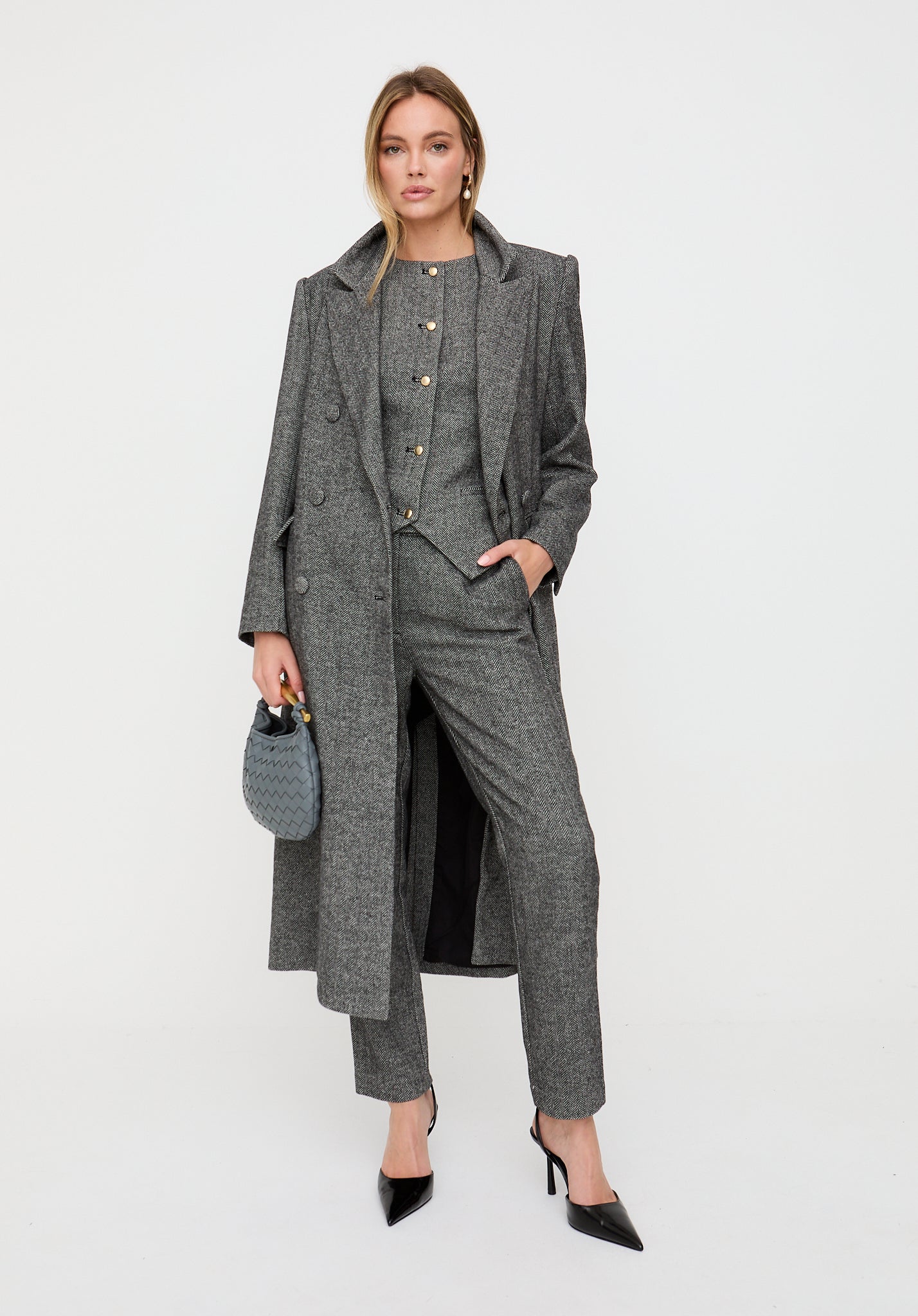 Woman wearing a gray suit with a long coat on a white background