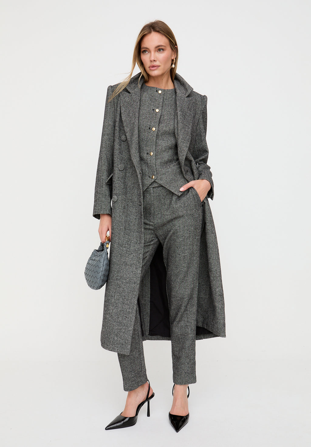 Woman wearing a gray suit with a long coat on a white background