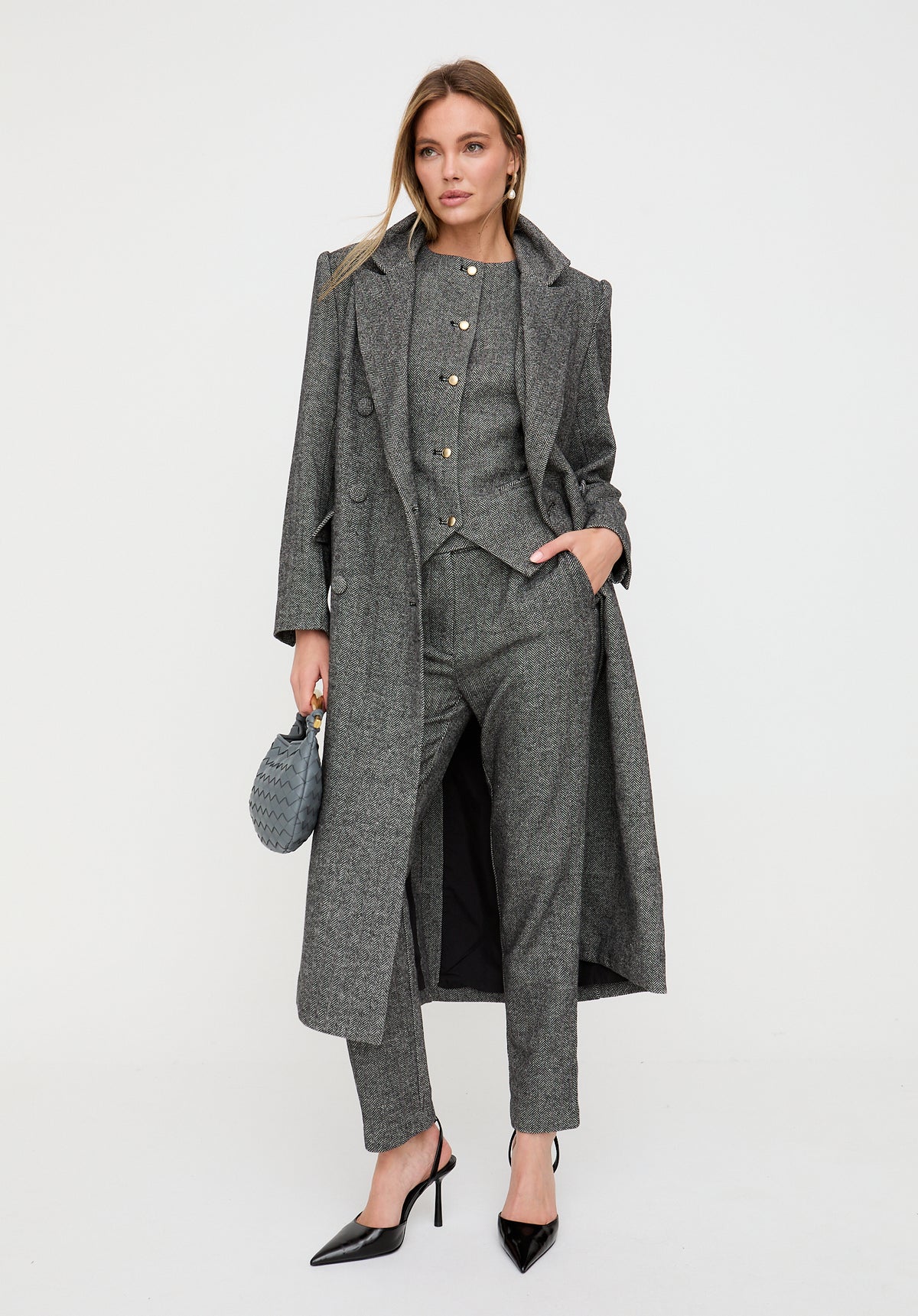 Woman wearing a gray suit with a long coat on a white background