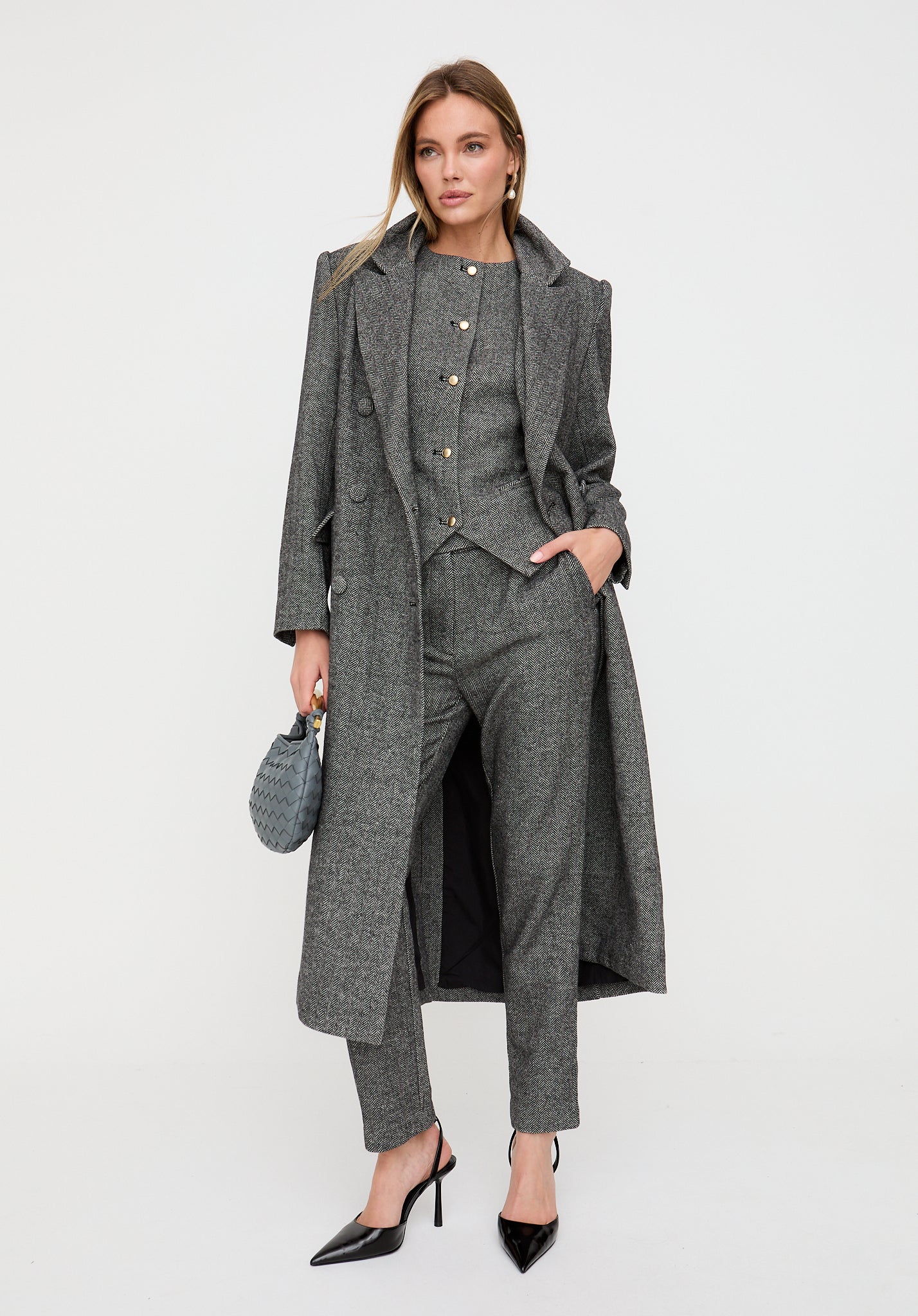 Woman wearing a gray suit with a long coat on a white background