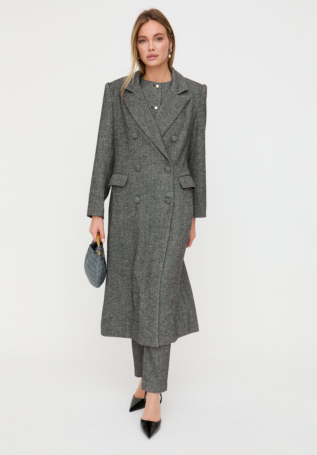 Woman wearing a gray coat and pants on a white background