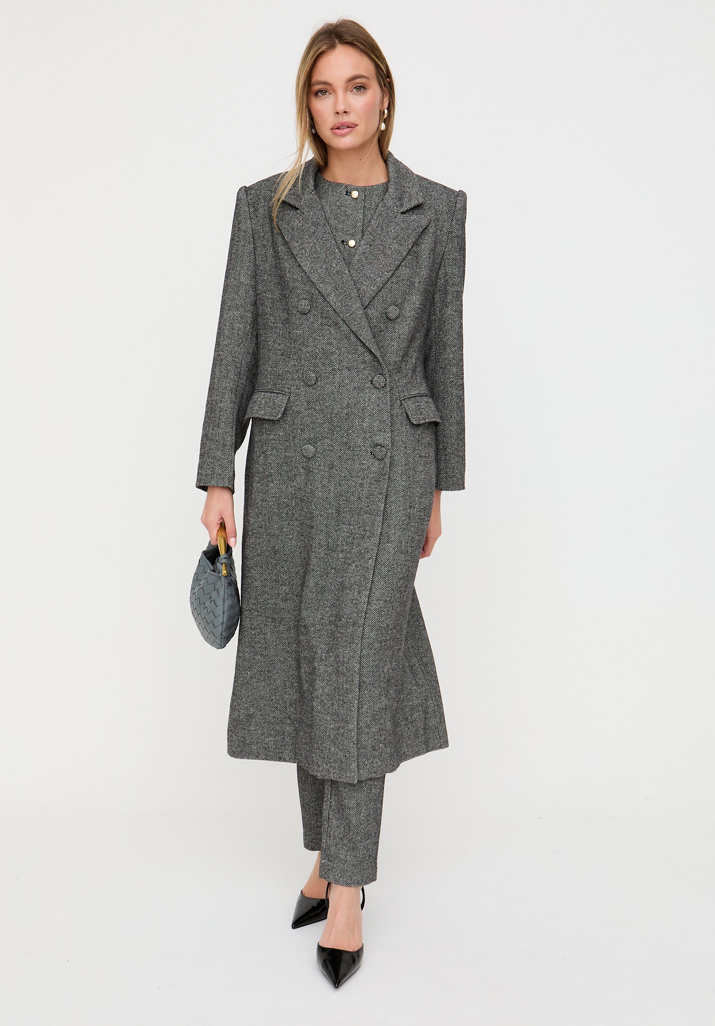 Woman wearing a gray coat and pants on a white background