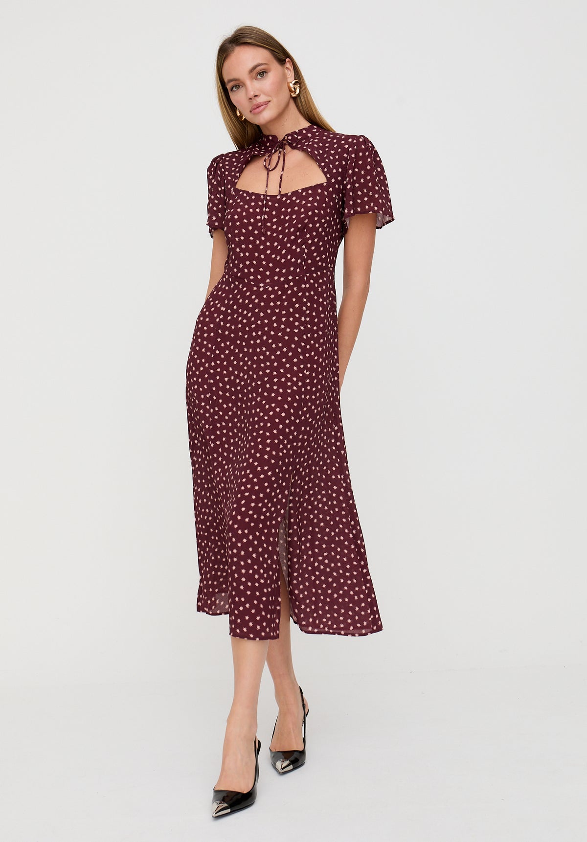 Woman wearing a burgundy dress with white polka dots on a white background