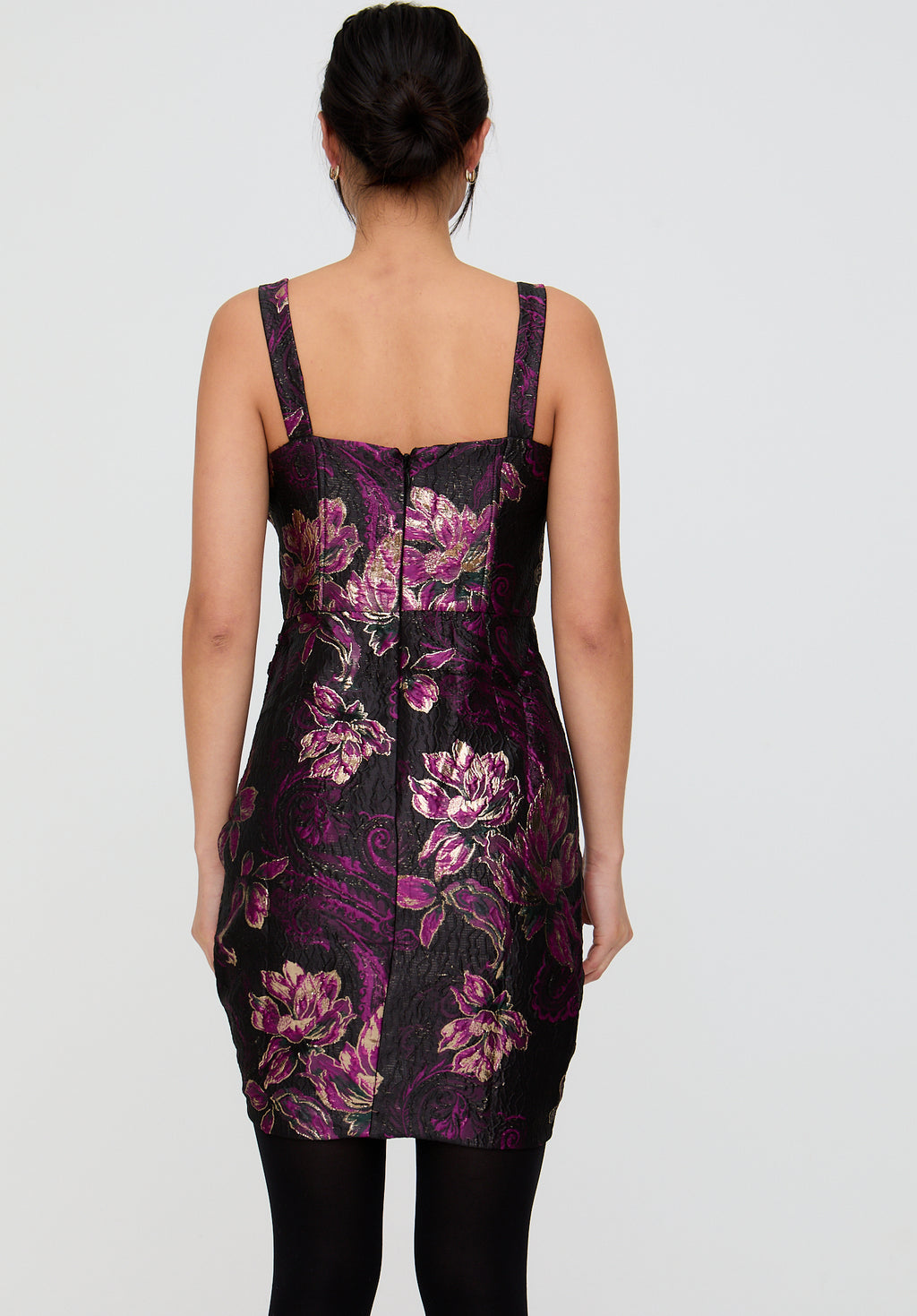 Woman wearing a black dress with purple floral pattern on a plain background