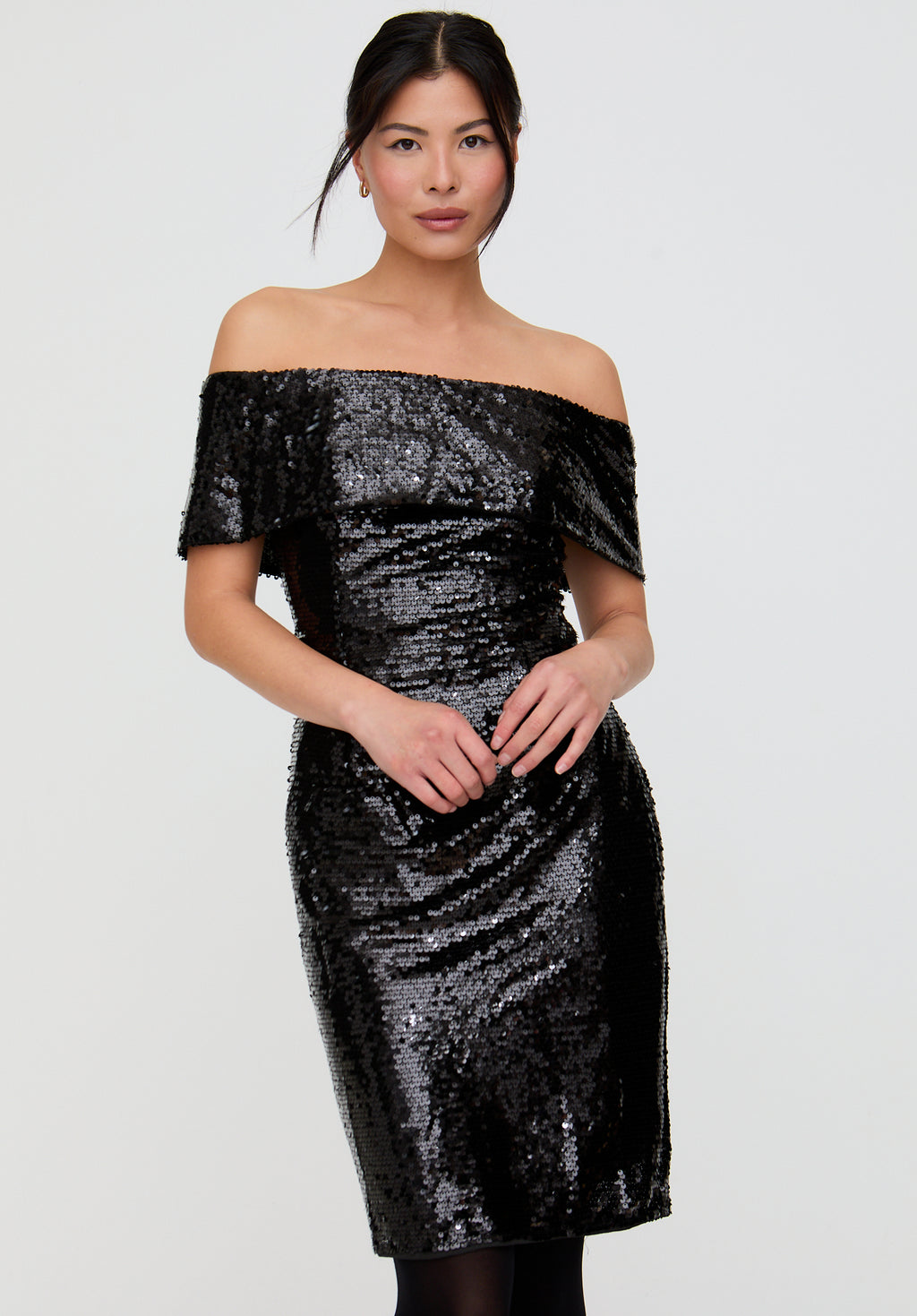 Woman wearing a black sequin off-shoulder dress on a white background