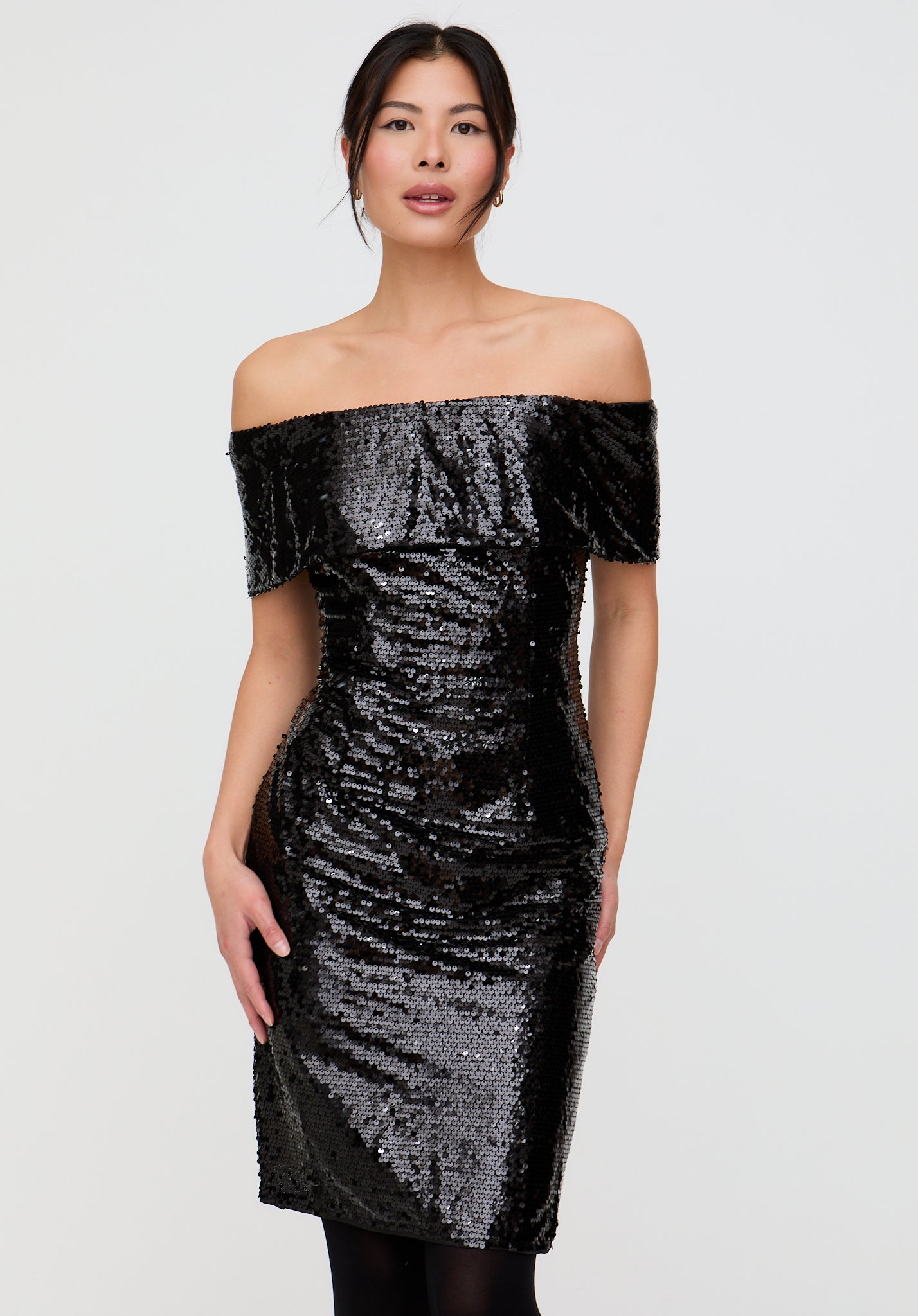 Woman wearing a black sequin off-shoulder dress on a white background