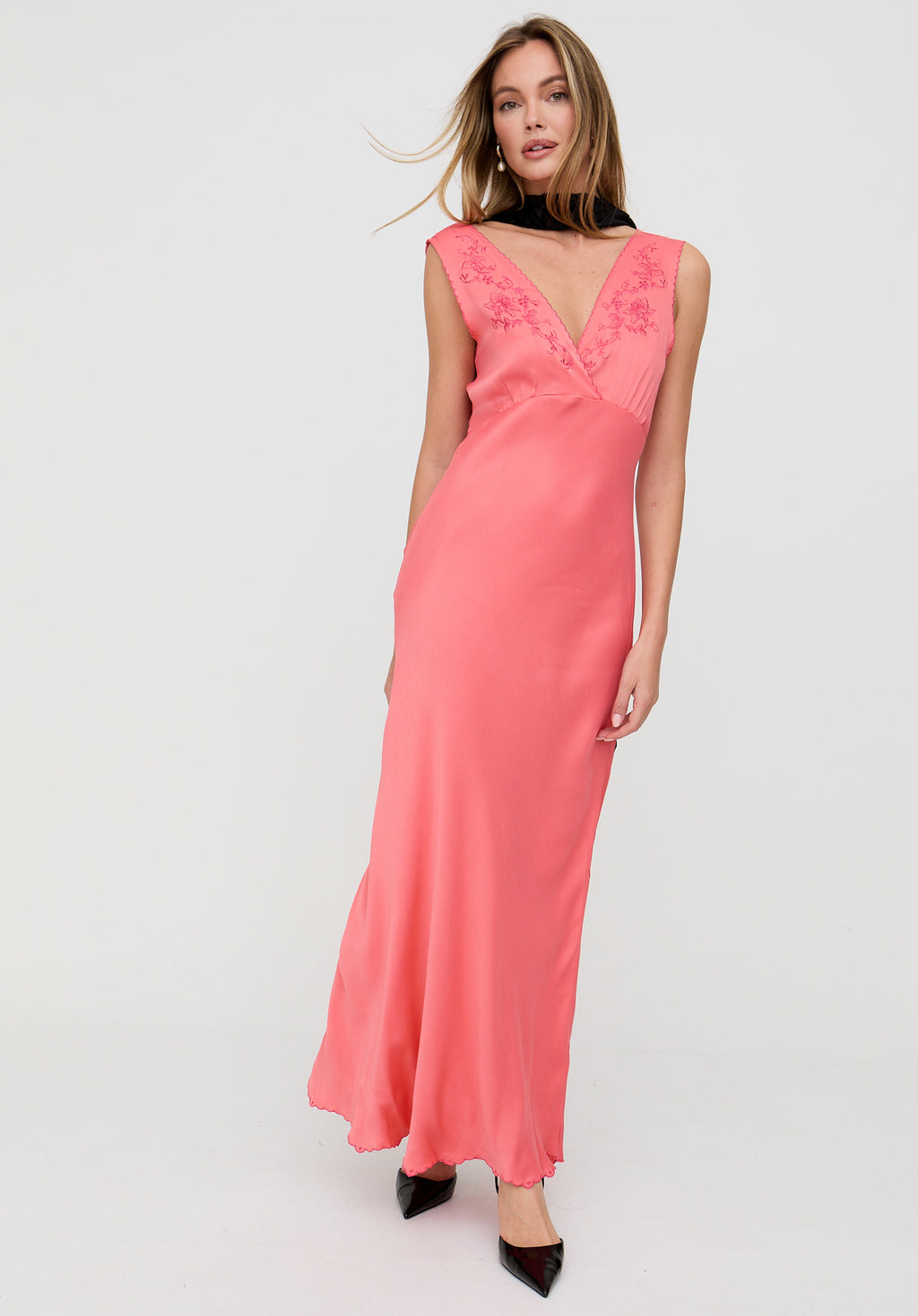 Woman wearing a pink dress with floral details on a white background