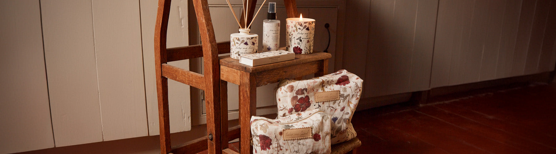 Collection of lifestyle products, including a candle, diffuser, pillow spray, wash bag and cosmetic bag in our cream pressed floral print.