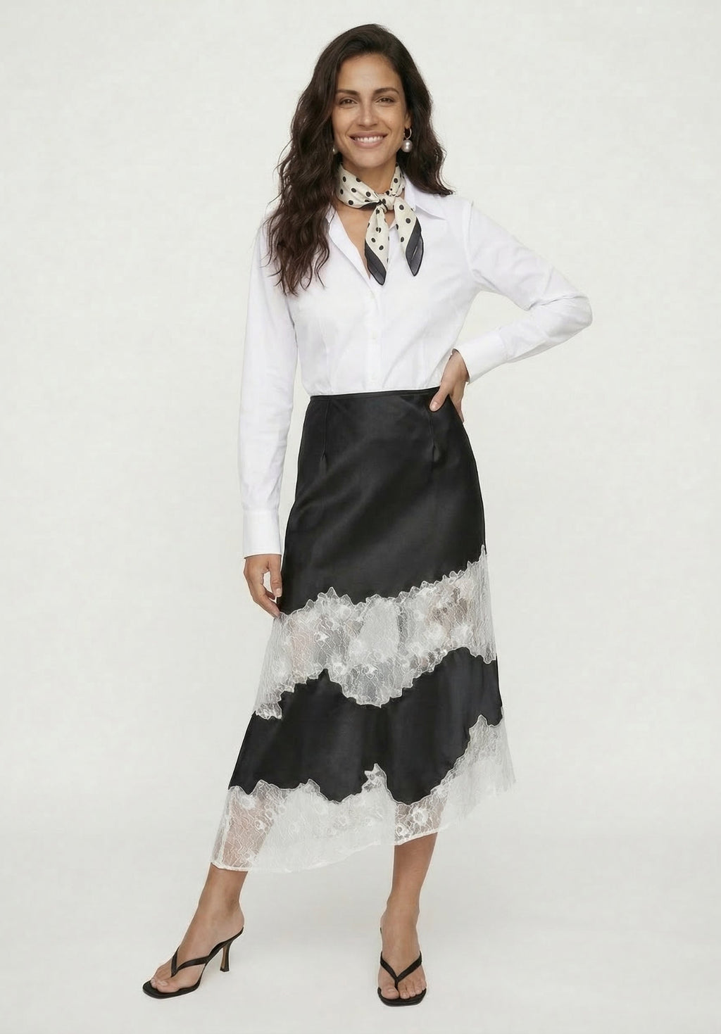 Woman wearing a white blouse and black lace skirt on a white background