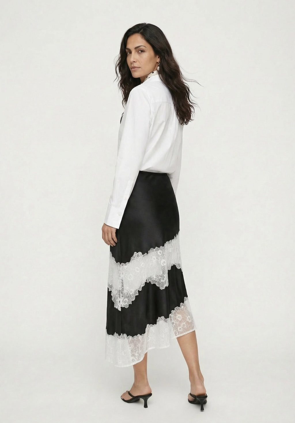 Woman wearing a white blouse and black and white lace skirt on a white background