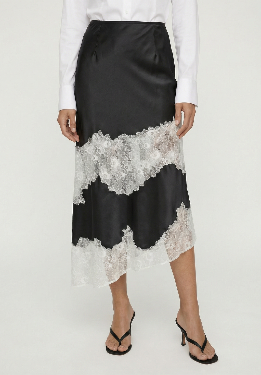 Black satin skirt with lace trim worn by a person on a white background