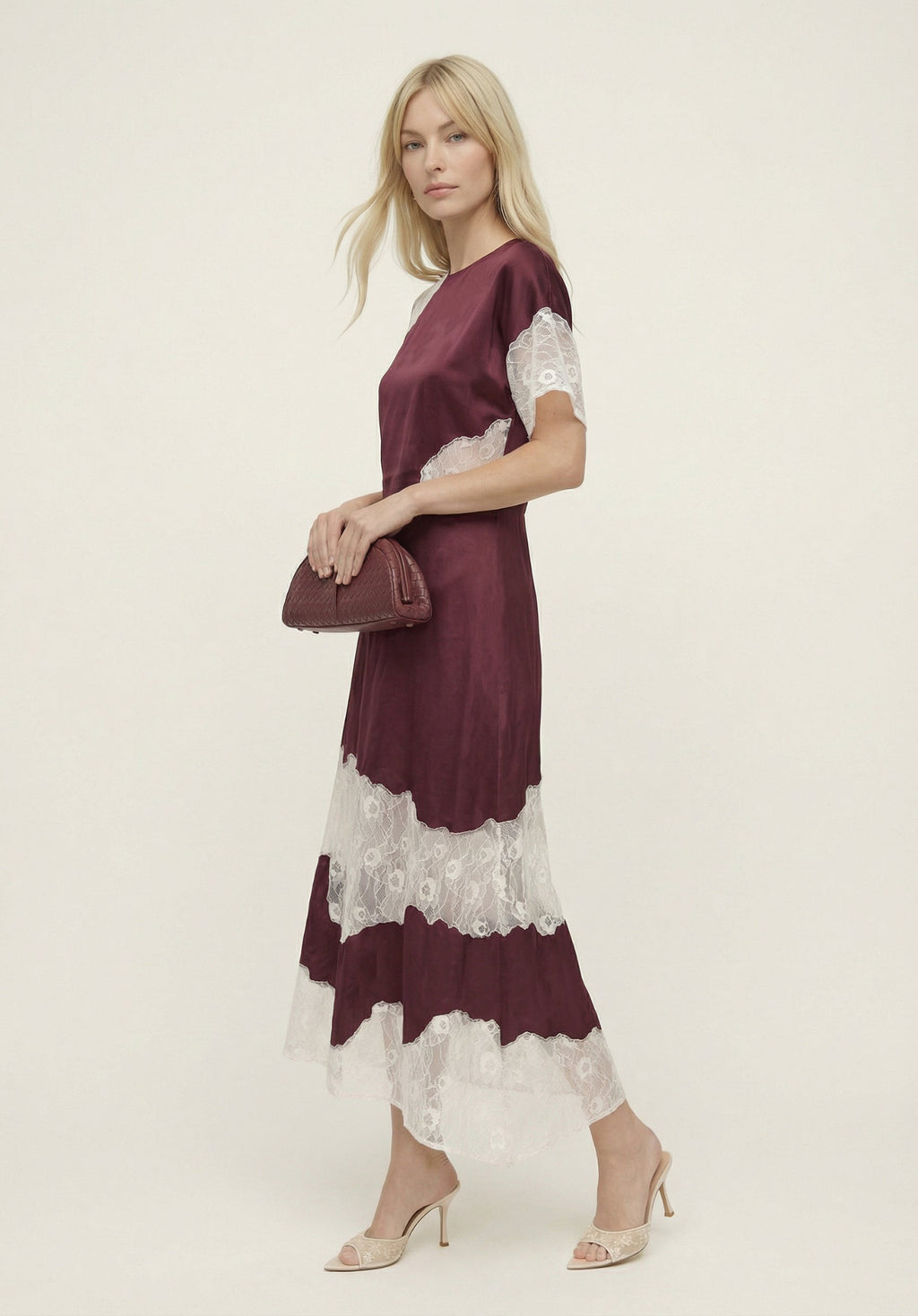 Woman wearing a burgundy and white lace dress on a plain background