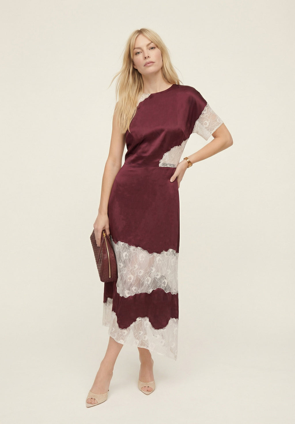 Woman wearing a burgundy and white dress with lace details on a beige background