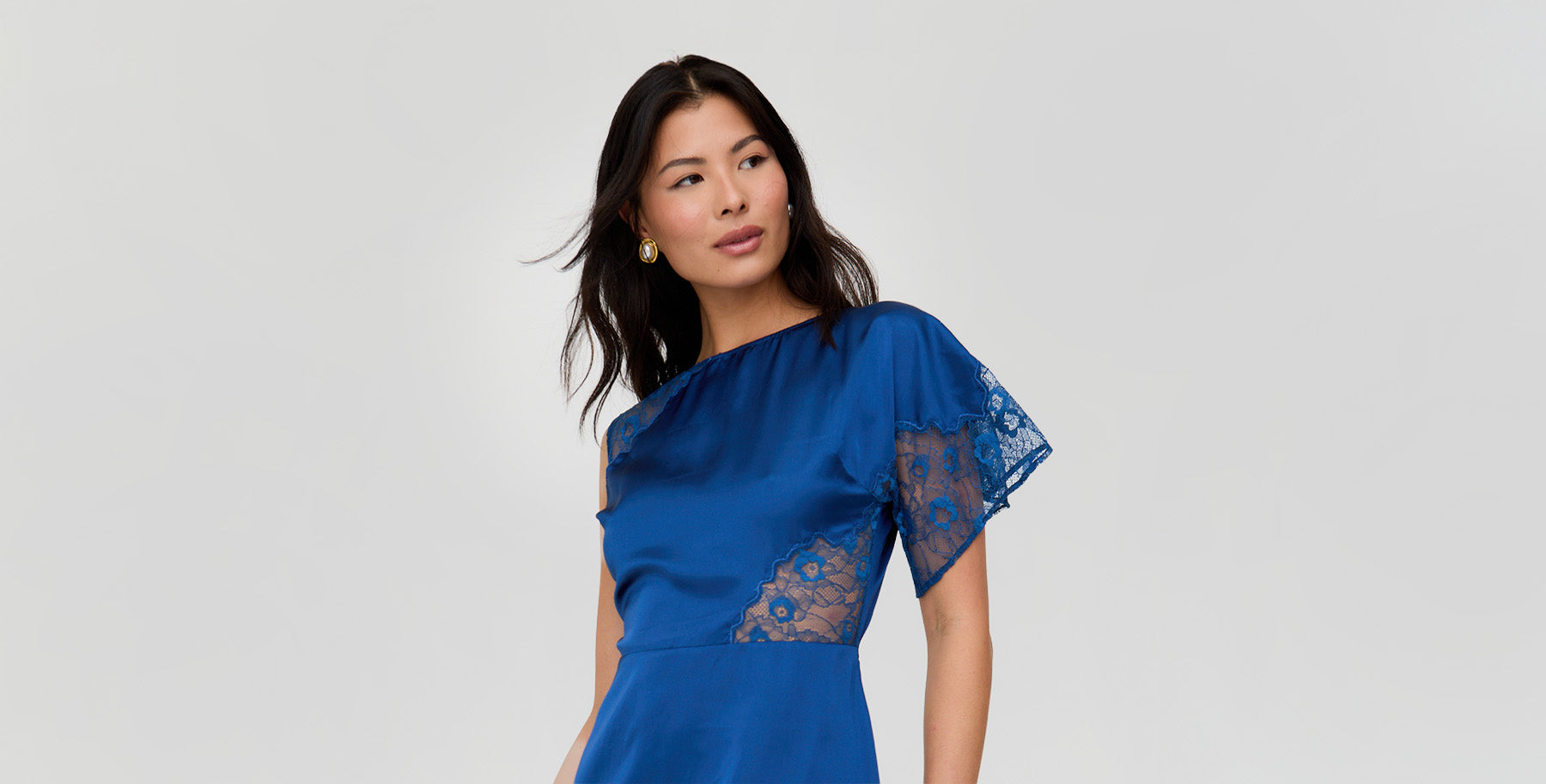 Woman wearing a blue dress with lace sleeves on a gray background