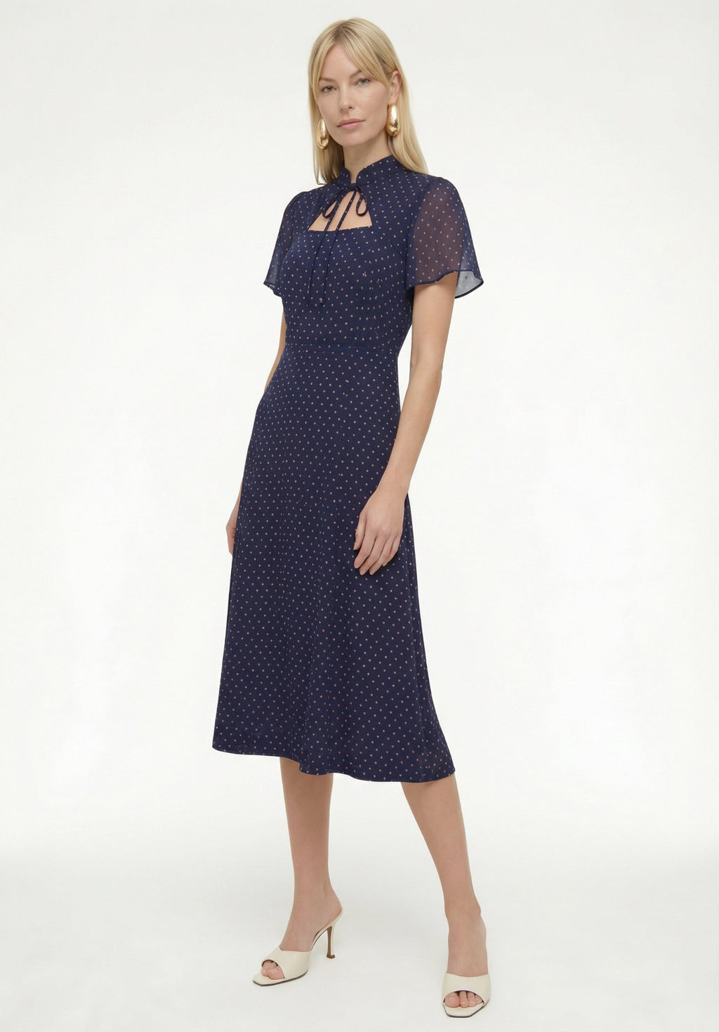 Woman wearing a navy dress with white polka dots on a white background