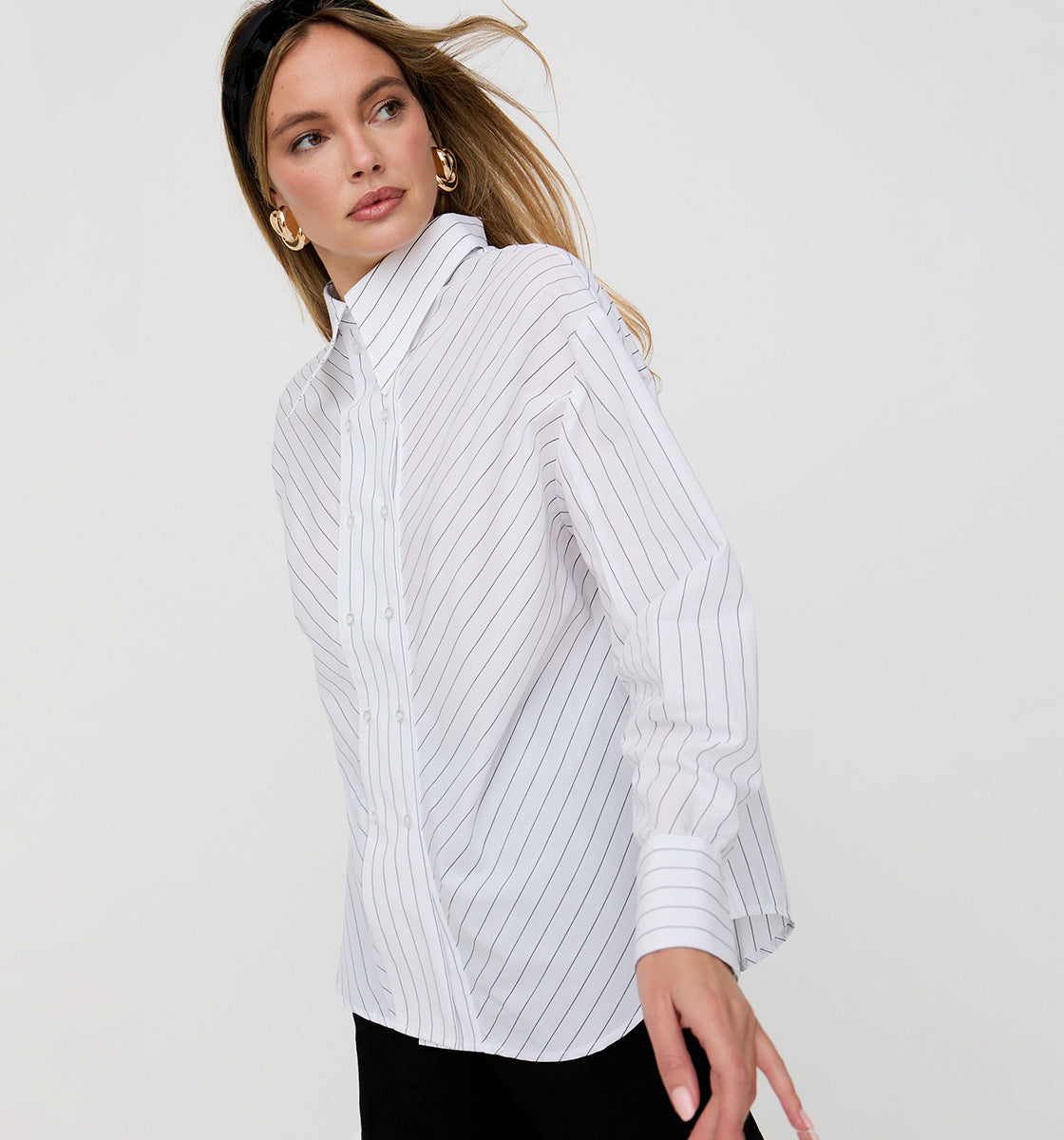 Woman wearing a white striped shirt against a plain background